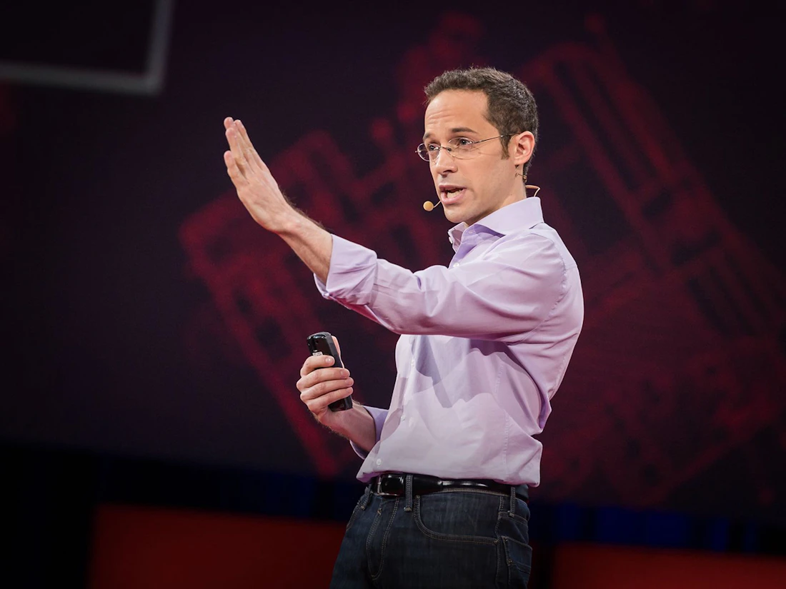 David Epstein speaking onstage with one hand raised