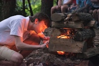 Boy lighting fire at summer camp.jpg?ixlib=rails 2.1